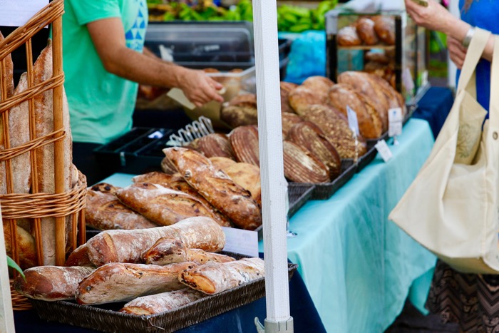 Customer surveying loaves of bread at a farmer's market.