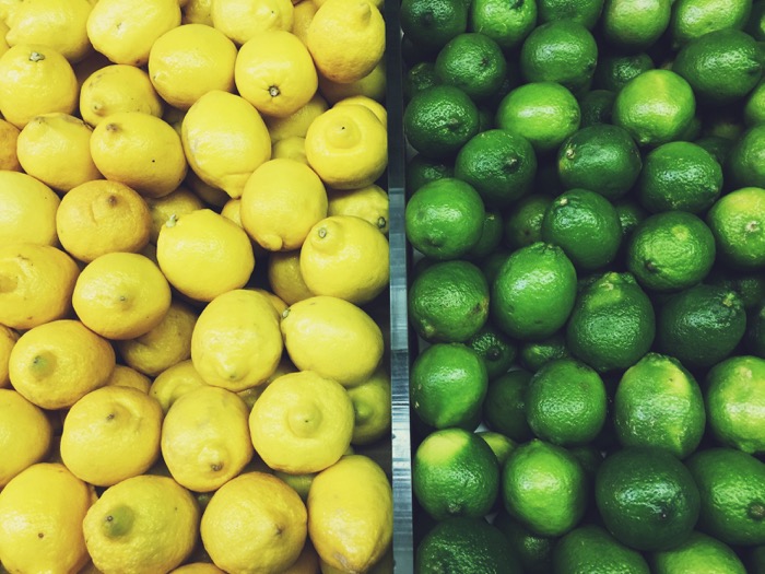 Overhead view of produce: lemons on the left side, and limes on the right side.