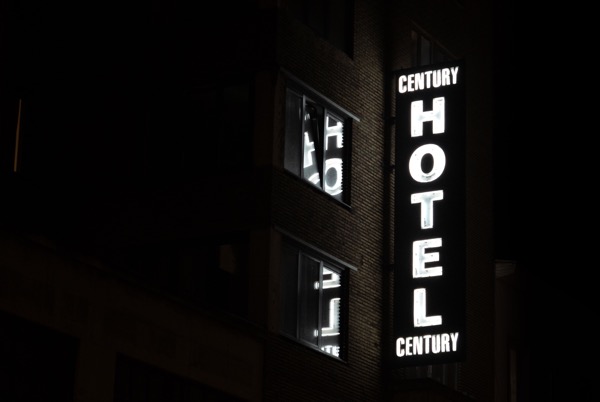 Picture of the exterior of a hotel at night with a sign that says "Century Hotel."