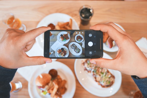A person taking a picture of a plate of food which is an easy restaurant marketing tips. 
