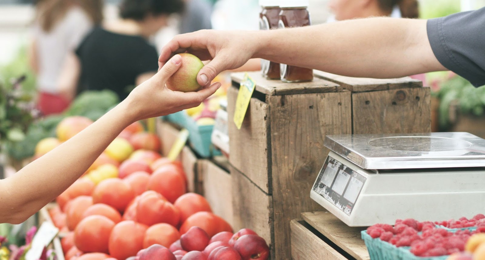 Fresh produce department scene: a small person hands a piece of fruit to a clerk to weigh on a scale. Learn how automation in grocery stores can save you time and money.