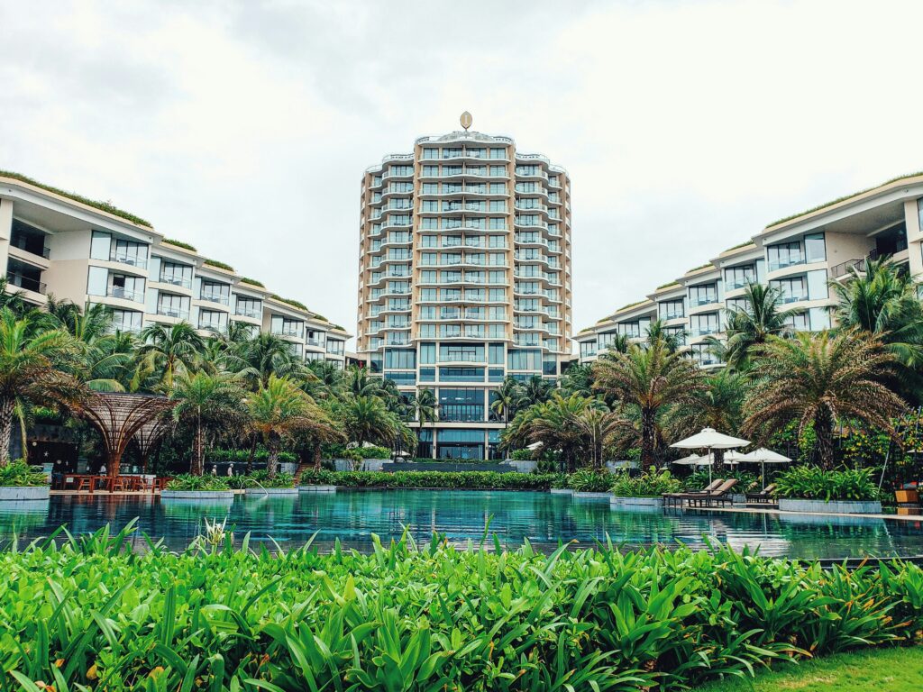 Picture of the exterior of a tall hotel building with an outdoor pool area.