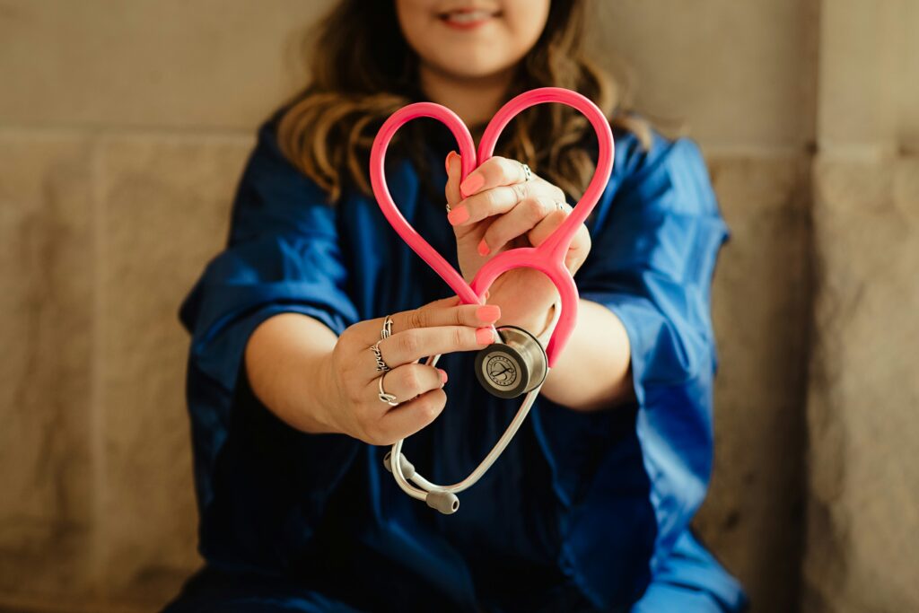 A nurse holds up their pink stethoscope in the shape of a heart.