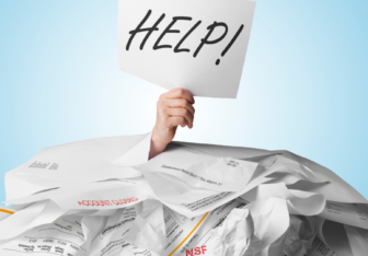 Office worker buried in a pile of paper holding a sign that says help!