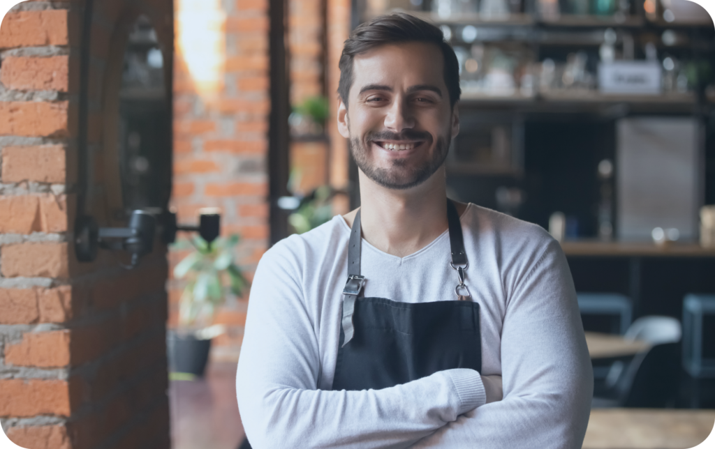 Happy male hospitality worker standing in a brick restaurant