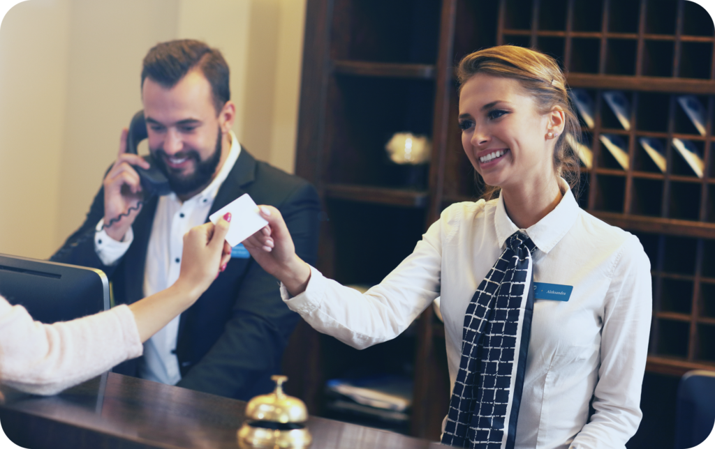 happy hospitality workers checking a guest in at a hotel reception deck