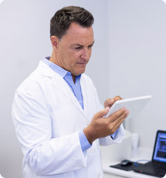 Doctor in lab coat examining a tablet in a medical office