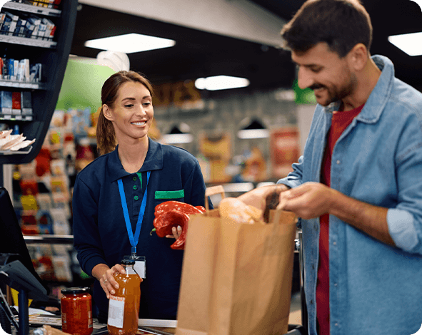 Grocery store worker helps male customer bag groceries